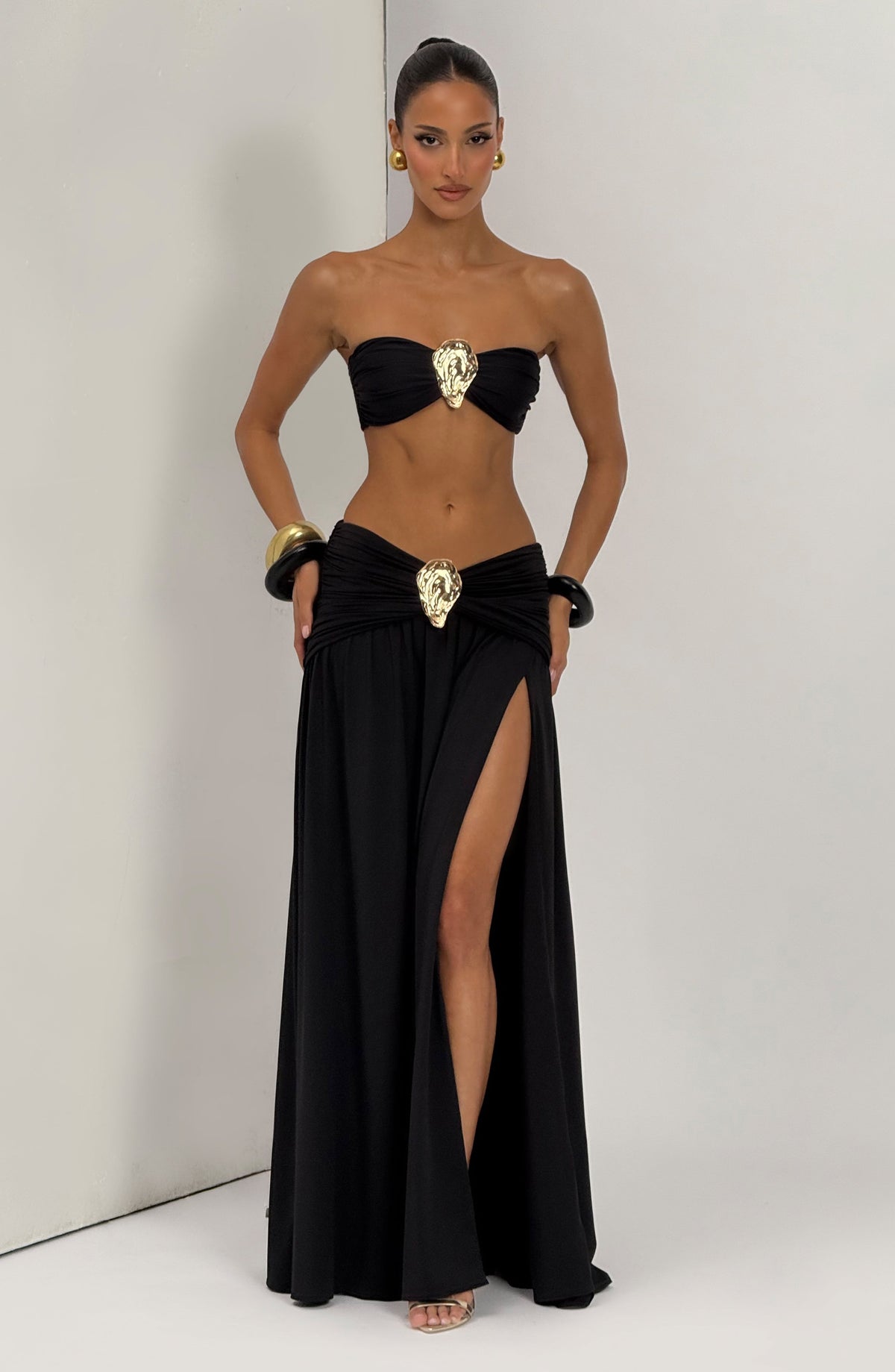 Top de bikini bandeau negro con broche central dorado y escote recto