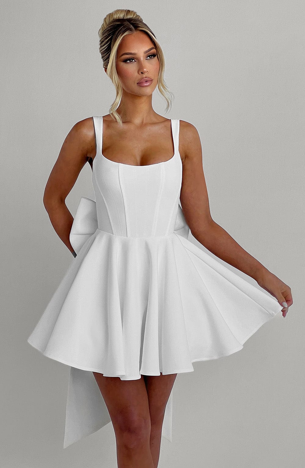Vestido blanco de tirantes finos con escote cuadrado y falda evasé acampanada con pliegues.